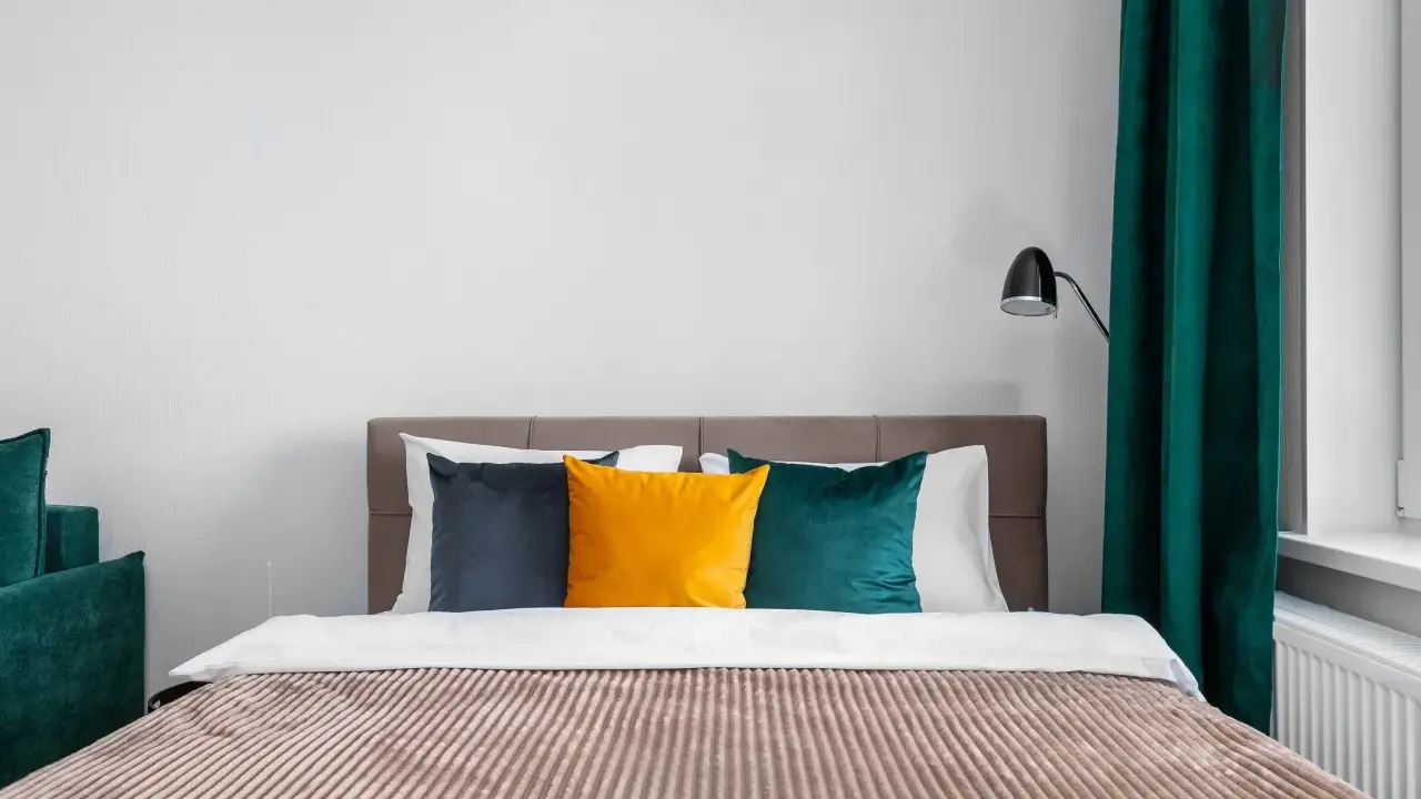 Lit de chambre cabine avec coussins colorés et rideaux verts.