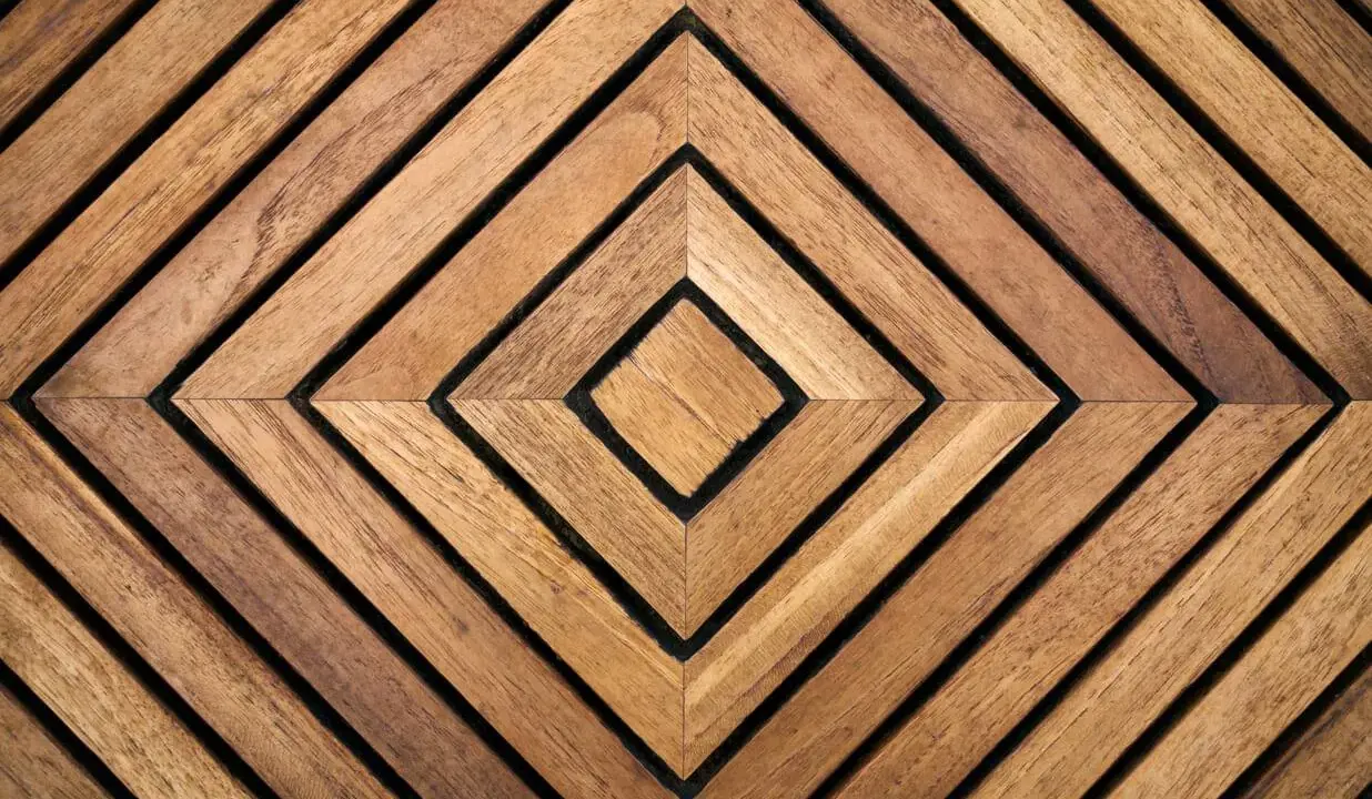 Motif géométrique en marqueterie contemporaine, alternant des bandes de bois brun clair et foncé formant des losanges imbriqués.