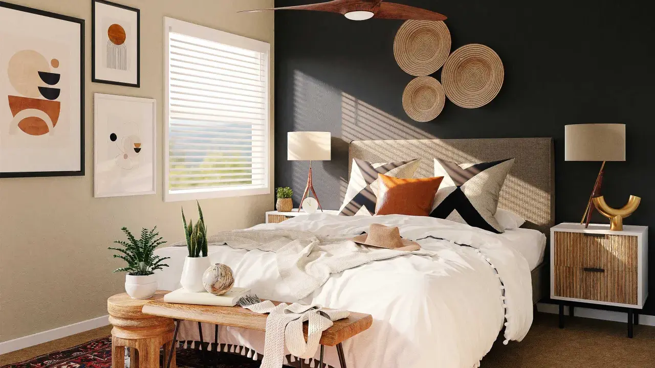 Une chambre moderne avec une décoration murale en vannerie, des tableaux abstraits et un ventilateur de plafond. Le lit est fait de blanc, avec des coussins graphiques et une touche de couleur ocre.