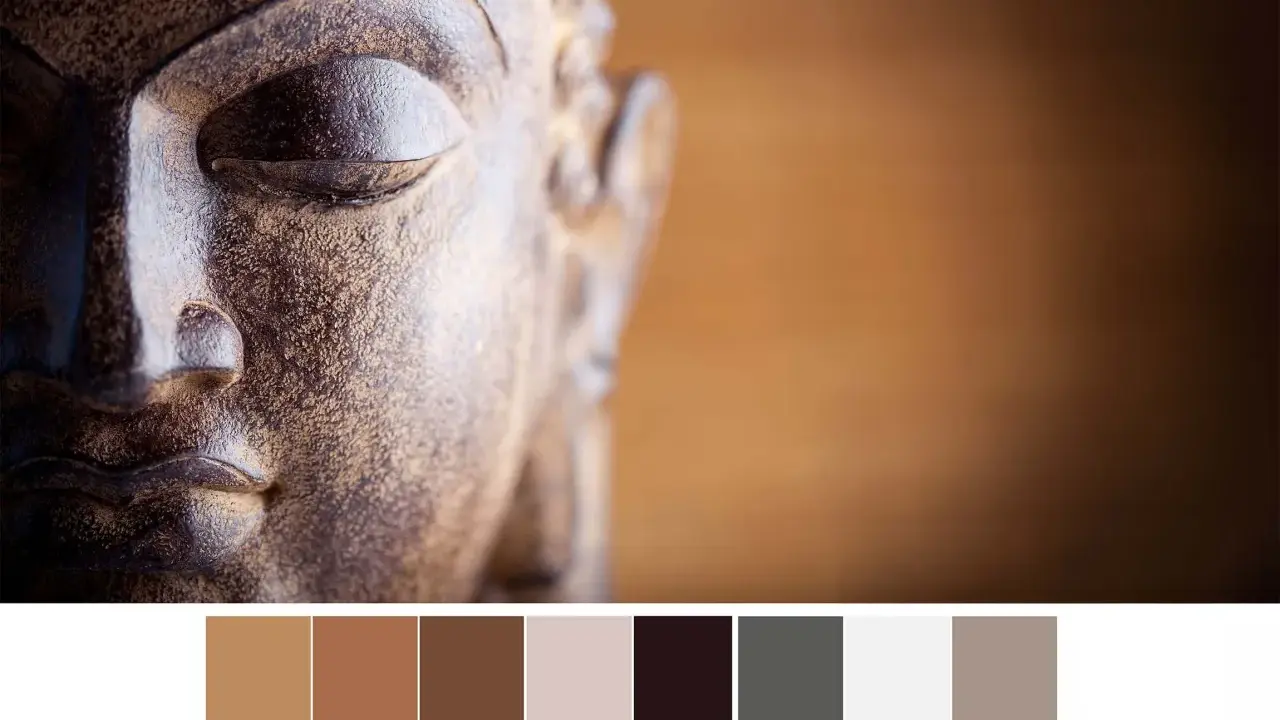 Gros plan sur le visage d'une statue de Bouddha aux tons terreux, avec une palette de couleurs apaisantes.