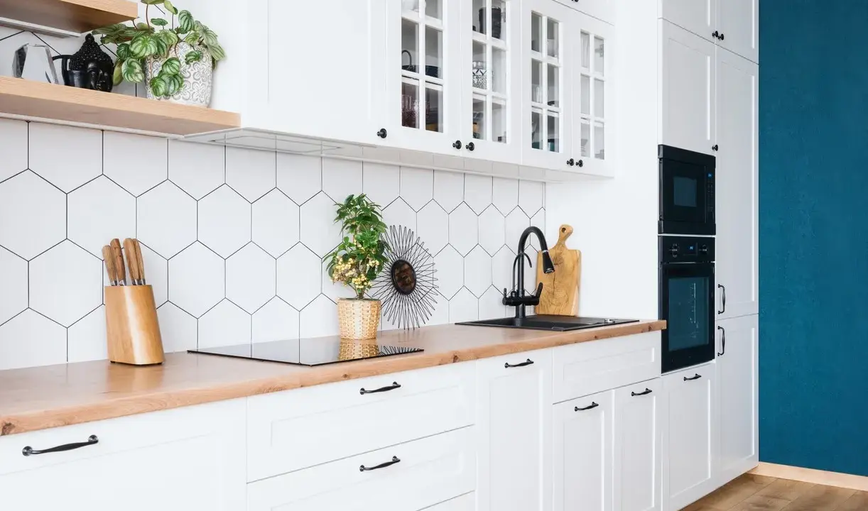 Cuisine moderne et lumineuse avec carrelage hexagonal blanc, plan de travail en bois et meubles blancs. Idéal pour refaire sa cuisine petit budget.