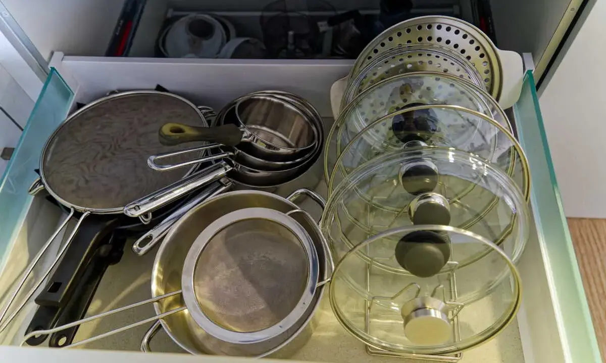 Tiroir de cuisine bien organisé avec une astuce pour ranger les couvercles de casseroles et poêles en verre et métal.