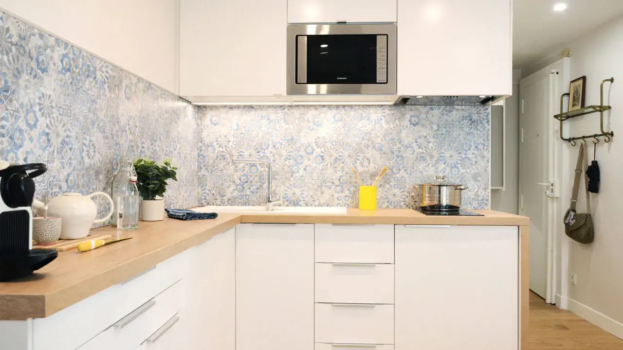 Cuisine moderne avec crédence carrelée bleu et blanc, plans de travail en bois et meubles blancs. Une idée pour une crédence cuisine blanche et originale.