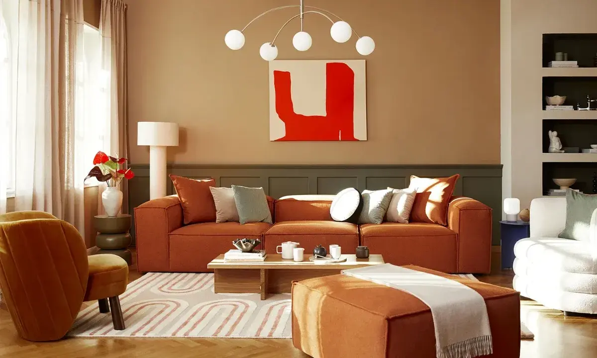 Salon chaleureux avec canapé orange, fauteuil assorti et tapis graphique. Un excellent conseil couleur peinture pour une ambiance cosy.