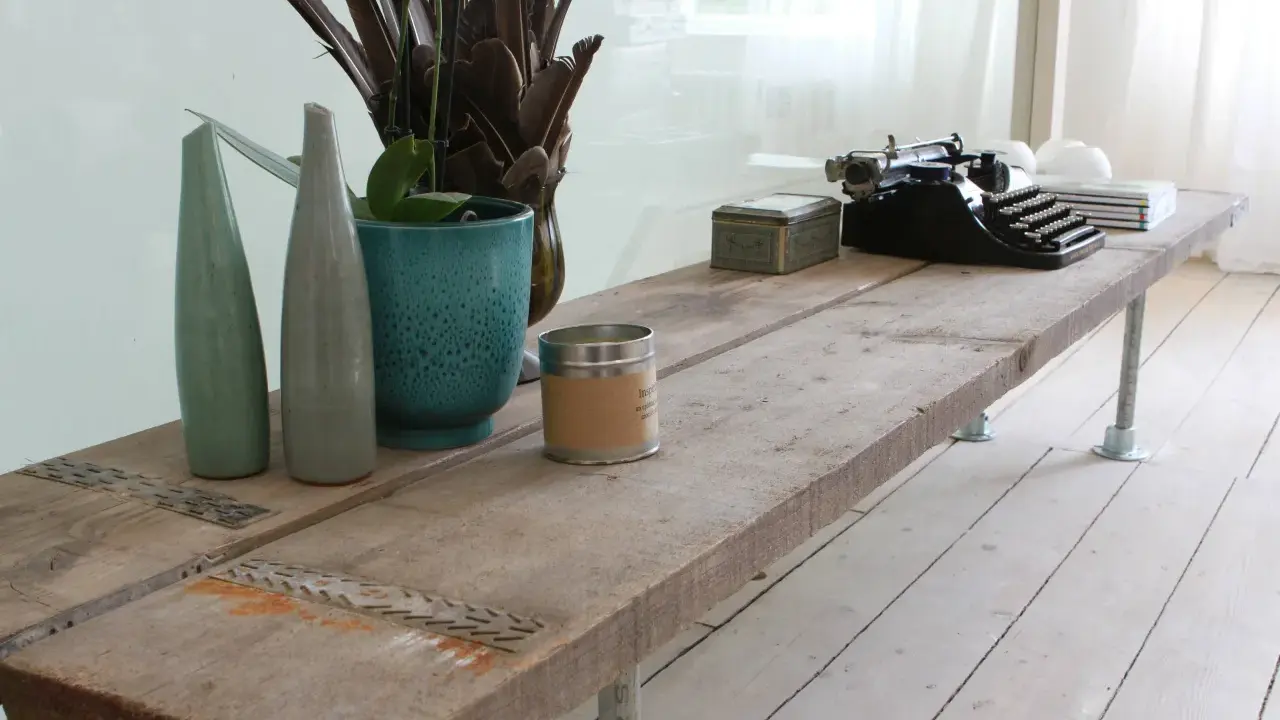 Une table basse rustique, idéale pour savoir que faire avec des vieilles planches de bois. Elle est décorée d'une machine à écrire vintage, de vases et d'une bougie.
