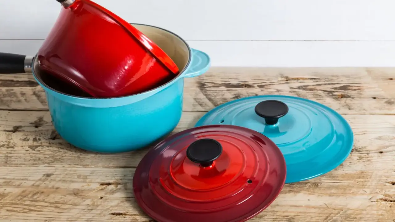 Une astuce rangement casserolier : une cocotte bleue empilée avec une rouge à l'intérieur, et deux couvercles colorés à côté.