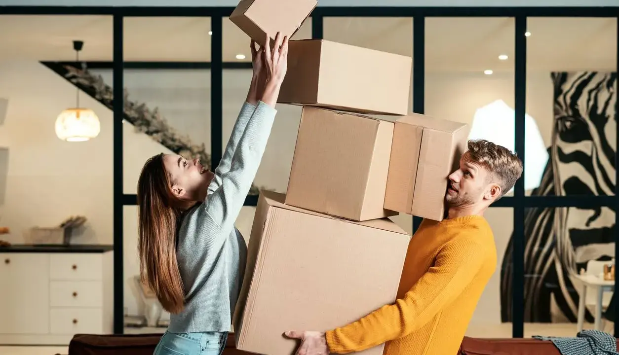 Couple jonglant avec des cartons. Difficile de savoir combien de cartons pour un déménagement quand on est aussi désorganisé !