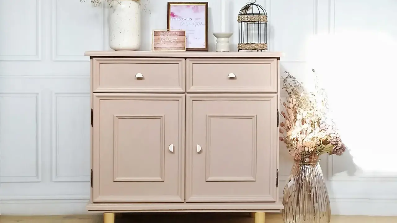 Meuble bas rose poudré, prêt à repeindre, avec deux tiroirs et deux portes. Décoré de fleurs séchées et d'une cage ornementale.
