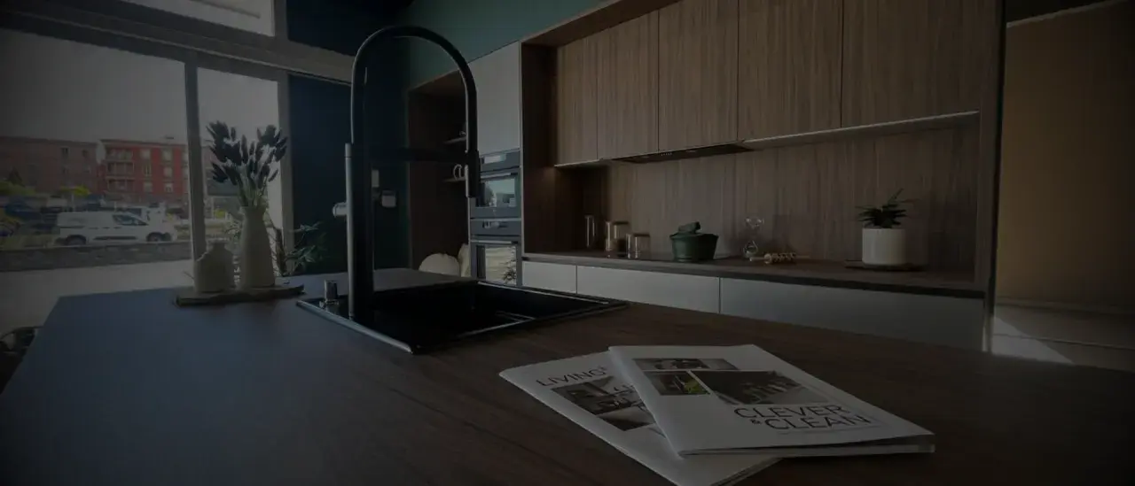 Cuisine moderne avec îlot central, robinetterie noire et magazines sur le plan de travail. Idéal pour rénover une cuisine.