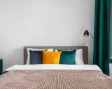 Lit de chambre cabine avec coussins colorés et rideaux verts.