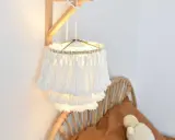 Un abat jour DIY en macramé blanc, avec des franges douces, éclaire une chambre cosy.