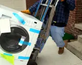 Un homme utilise un chariot pour comment monter une machine à laver dans les escaliers.