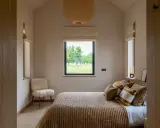 Aménagement petite chambre cosy avec lit douillet, fauteuil mouton et vue sur la nature.
