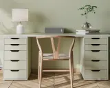 Un bureau DIY épuré avec une chaise en bois, une lampe, un haut-parleur et une plante.