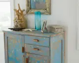 Meuble patiné bleu délavé, orné d'objets marins et d'une boîte décorative.
