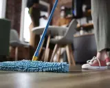 Nettoyage avant déménagement : une personne passe une serpillère bleue sur un parquet.