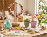 Table de bricolage pour décoration printemps à fabriquer : couronne de fleurs séchées, pots peints, tulipes, et matériel créatif.