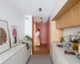 Cuisine moderne et lumineuse avec îlot central, décoration murale et personne marchant au fond.