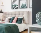Une belle idée de tête de lit capitonnée, avec des coussins verts et roses, des plantes et des cadres botaniques.