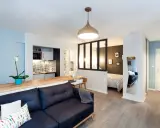 Aménagement studio 30m2 : salon cosy, cuisine moderne, coin repas et chambre séparée par une verrière.