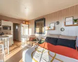 Aménagement d'un plan studio 20m2 en longueur : coin cuisine, lit confortable, fauteuils en rotin et décoration murale zen.
