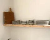 Étagère en bois brut, parfaite pour une cuisine de style **diy etagere bois**. Elle accueille une planche à découper, des assiettes, des bols et des bougies.