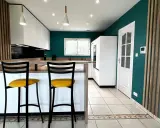 Cuisine moderne aux murs bleu canard, îlot central en bois, tabourets jaunes vifs. Une véritable inspiration cuisine pour des repas conviviaux.