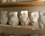 Plusieurs torses féminins en argile autodurcissante, prêts pour un projet diy, sont alignés sur une étagère en bois.