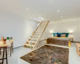 Aménager un sous-sol en pièce habitable : un lit douillet, un bureau fonctionnel et un escalier moderne créent un espace de vie confortable.