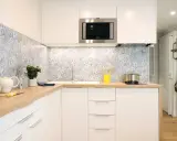 Cuisine moderne avec crédence carrelée bleu et blanc, plans de travail en bois et meubles blancs. Une idée pour une crédence cuisine blanche et originale.