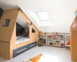 Chambre d'enfant aménagée sous les combles avec un lit cabane en bois, étagères remplies de jouets et livres. Un plan d'aménagement astucieux pour optimiser l'espace.