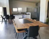 Grande cuisine ouverte sur salon, avec îlot central, table en bois et chaises modernes.