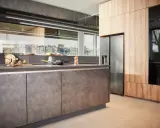 Une cuisine en plan moderne avec des armoires en bois et des surfaces sombres. Un réfrigérateur en acier inoxydable est visible.