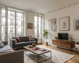 Un salon parisien avec un **mixer moderne et ancien** : canapés confortables, parquet, grandes fenêtres et une décoration chaleureuse.