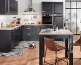 Cuisine 10m2 fermée, moderne et fonctionnelle avec des meubles noirs, un plan de travail en bois clair et un îlot central. Le sol est orné d'un motif géométrique.