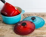 Une astuce rangement casserolier : une cocotte bleue empilée avec une rouge à l'intérieur, et deux couvercles colorés à côté.