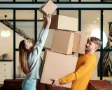 Couple jonglant avec des cartons. Difficile de savoir combien de cartons pour un déménagement quand on est aussi désorganisé !