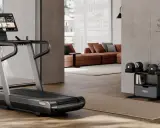 Un tapis de course et des haltères ajustables pour faire une salle de sport chez soi. Un espace moderne et fonctionnel pour le fitness à domicile.