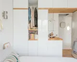 Chambre avec dressing intégré, organisée avec des étagères de livres et des vêtements suspendus. Un coin coiffeuse avec miroir et accessoires complète l'espace.