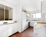 Relooker cuisine avant après : une cuisine moderne et lumineuse avec des meubles blancs, un plan de travail marbré et un sol hexagonal rouge.