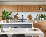Élégante déco cuisine moderne chic avec armoires en bois, îlot gris, plantes vertes et vaisselle en bois.