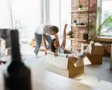 Un couple s'amuse en déménageant. Elle glisse dans un carton, un objet fragile, tandis qu'il la pousse.