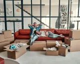 Couple se repose sur un canapé rouge entouré de cartons, signe d'un emménagement appartement réussi.