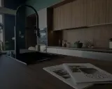 Cuisine moderne avec îlot central, robinetterie noire et magazines sur le plan de travail. Idéal pour rénover une cuisine.