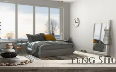 Une chambre apaisante avec un lit douillet, une pile de galets et le mot "FENG SHUI" en lettres métalliques.