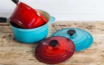 Une astuce rangement casserolier : une cocotte bleue empilée avec une rouge à l'intérieur, et deux couvercles colorés à côté.
