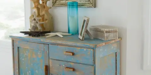 Meuble patiné bleu délavé, orné d'objets marins et d'une boîte décorative.