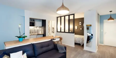 Aménagement studio 30m2 : salon cosy, cuisine moderne, coin repas et chambre séparée par une verrière.