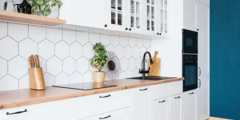 Cuisine moderne et lumineuse avec carrelage hexagonal blanc, plan de travail en bois et meubles blancs. Idéal pour refaire sa cuisine petit budget.