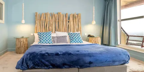 Tête de lit bois à faire soi-même, ambiance bord de mer avec coussins bleus et couverture marine.